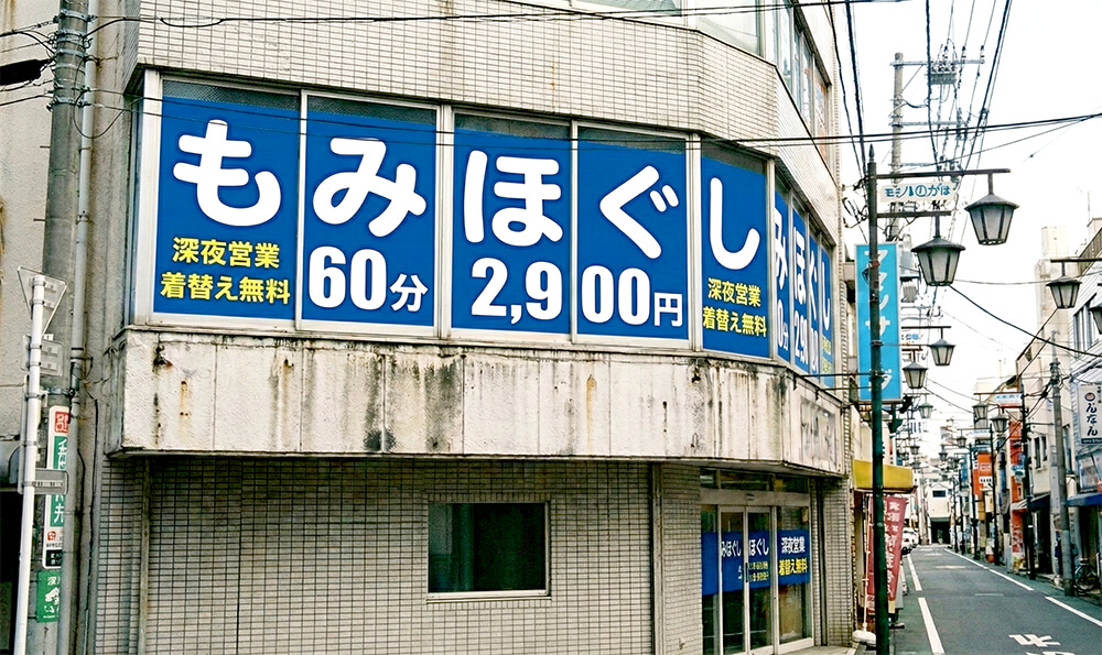 都内マッサージ店の2階窓全面に施工されたウィンドウサイン看板で価格強調