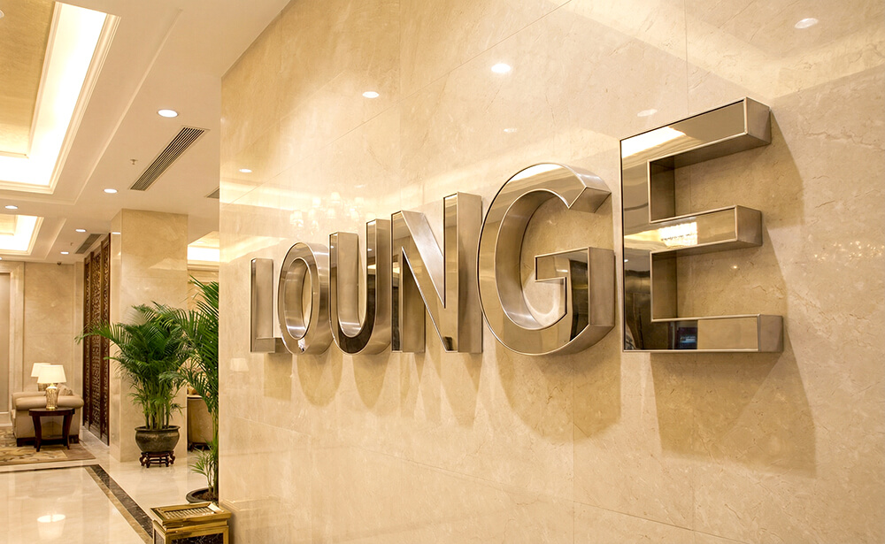 ホテルロビーの大理石壁面に、光らない鏡面ステンレス製のチャンネル文字ロゴが取り付けられている上品なイメージ。