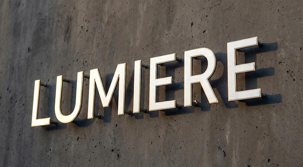 美容室のファサードデザイン：コンクリートの壁に設置された高級感のあるステンレス切り文字の看板