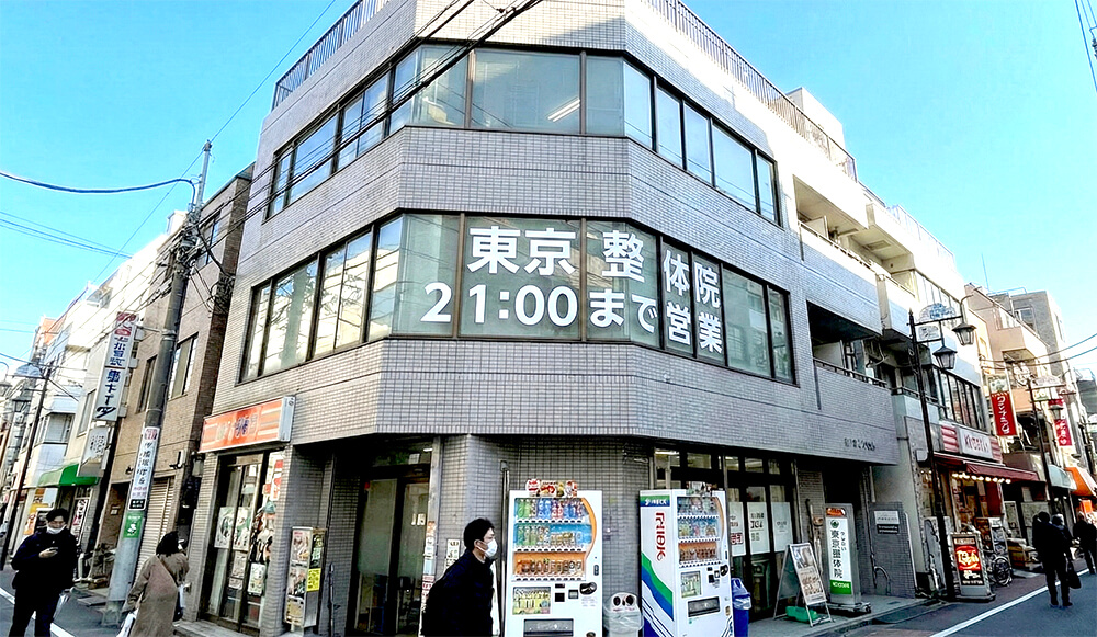 ビルの2階の窓ガラスに貼られた整体院の診療時間と院名のシートサイン